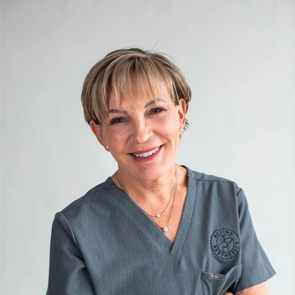Smiling professional in scrubs at Refine Aesthetics, a medical aesthetics clinic in Colorado Springs.