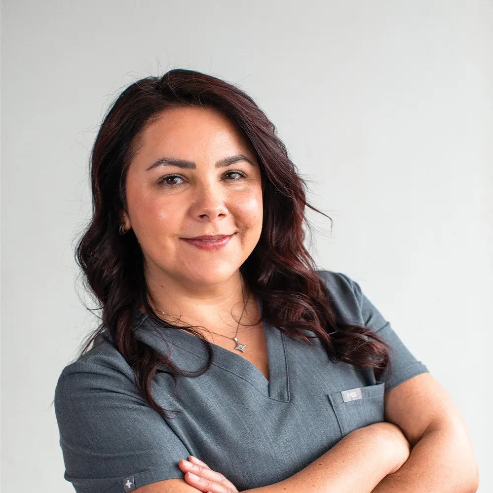 Smiling professional in scrubs representing Refine Aesthetics, a Colorado Springs medical aesthetics clinic.