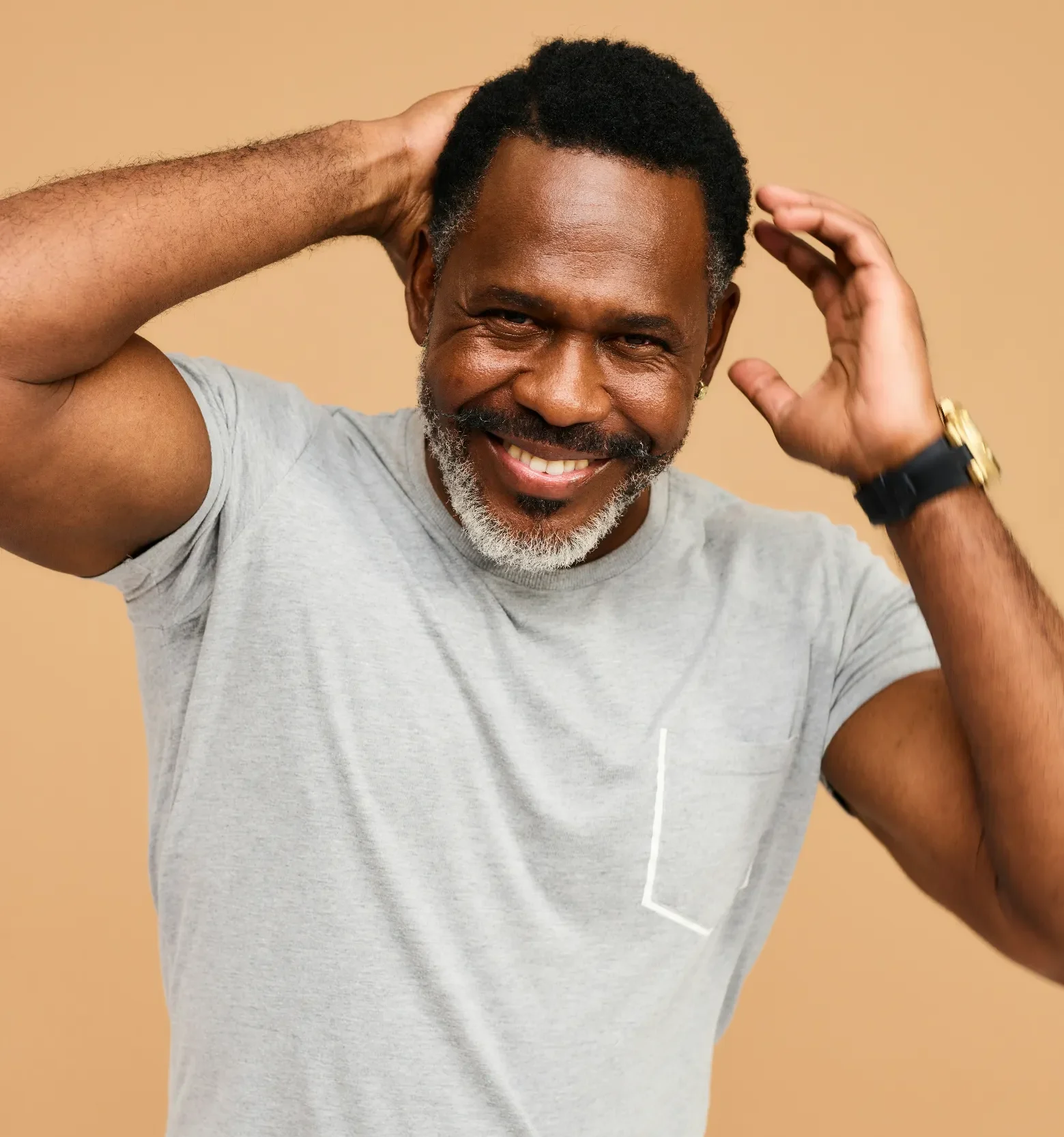 Smiling man in a casual gray shirt against a beige background.